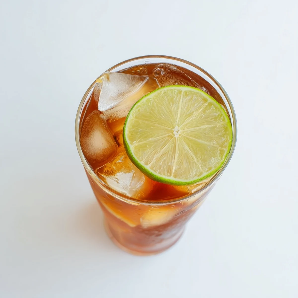 Tall glass of Thai lime iced tea with ice cubes and fresh lime slice garnish
