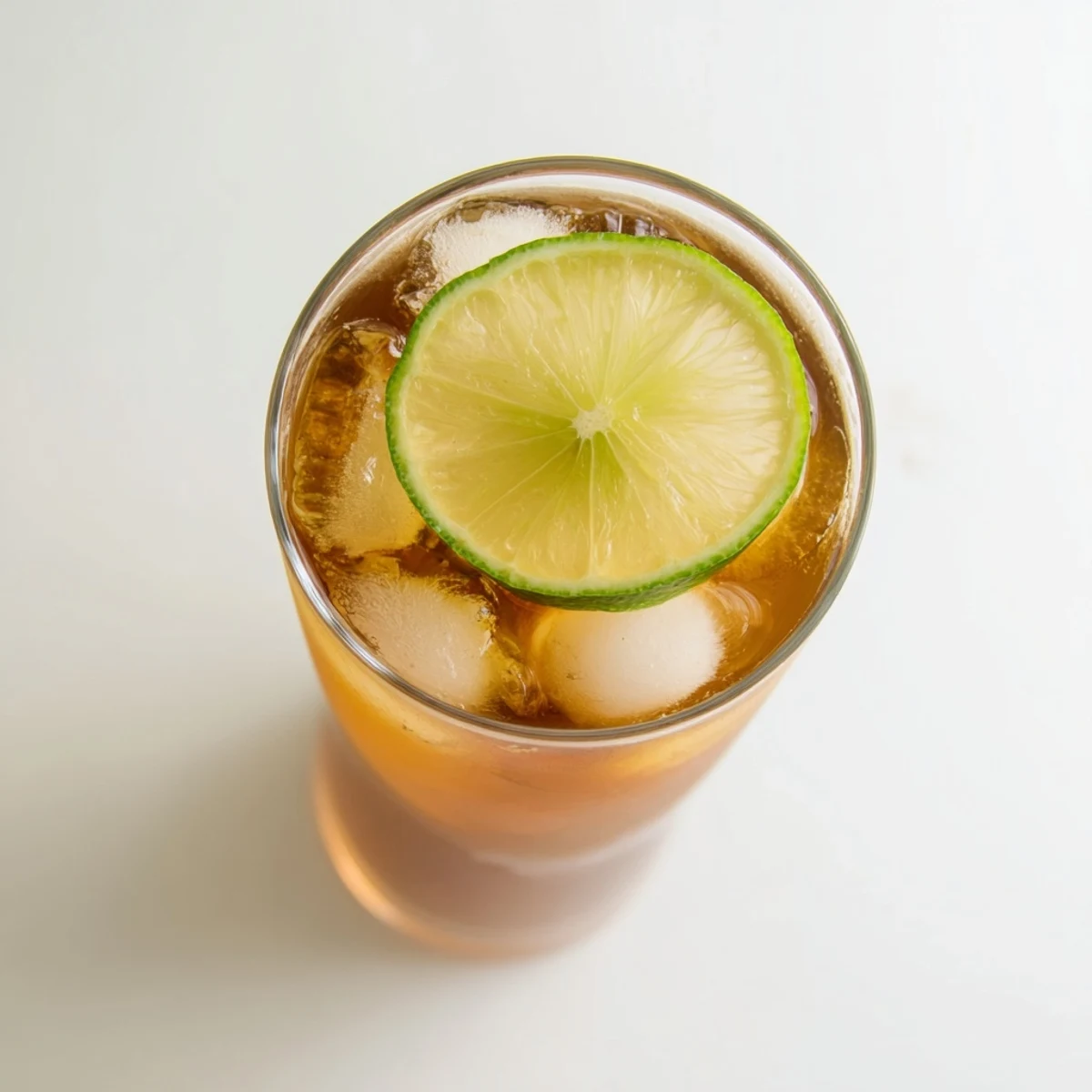 Golden Thai lime iced tea in clear glass filled with ice and citrus garnish