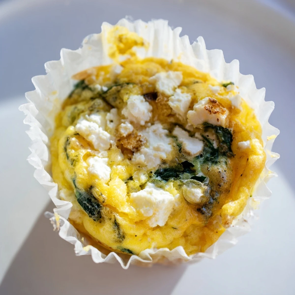 Savory egg muffins packed with fresh spinach and crumbled feta cheese on a white plate