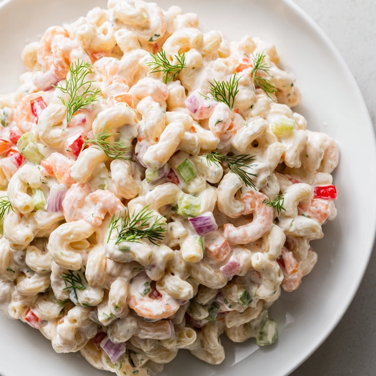 Chilled shrimp macaroni salad topped with fresh dill and colorful diced vegetables