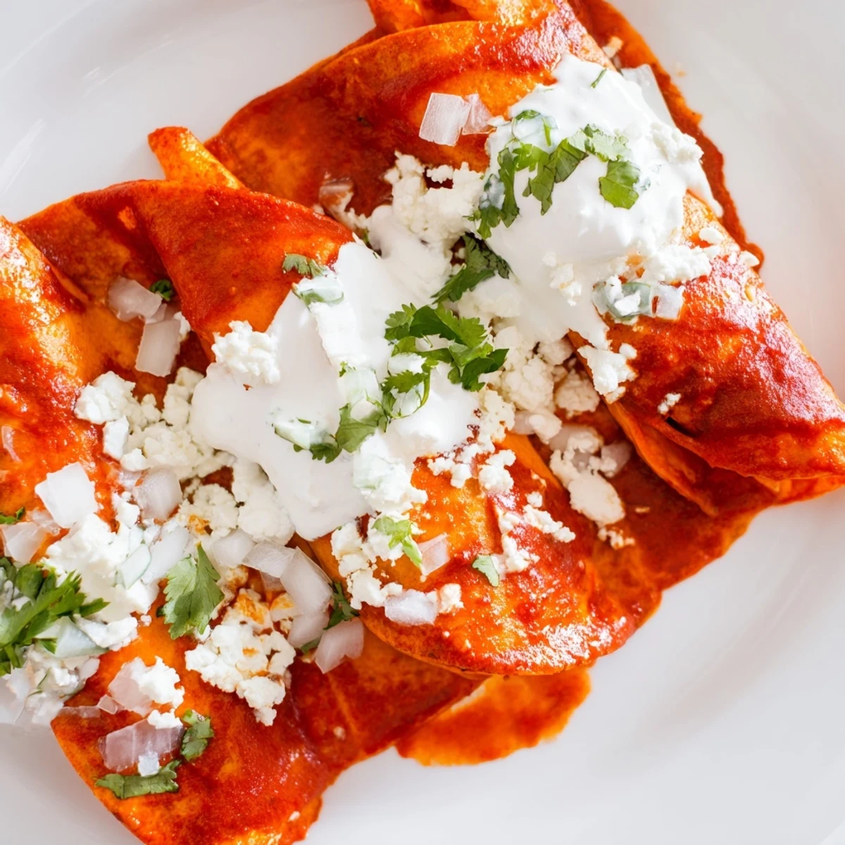 Warm corn tortillas folded into entomatadas swimming in vibrant homemade tomato sauce with crema drizzle