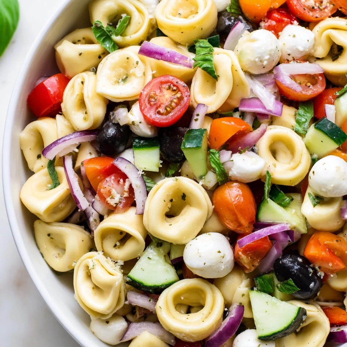 Colorful tortellini salad with cherry tomatoes, cucumber, and zesty Italian dressing in a serving bowl