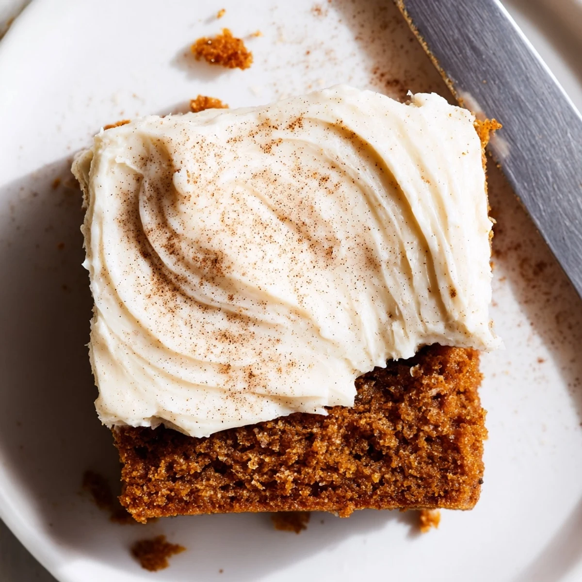 Creamy white frosting spread over spiced pumpkin bars dusted with warm cinnamon