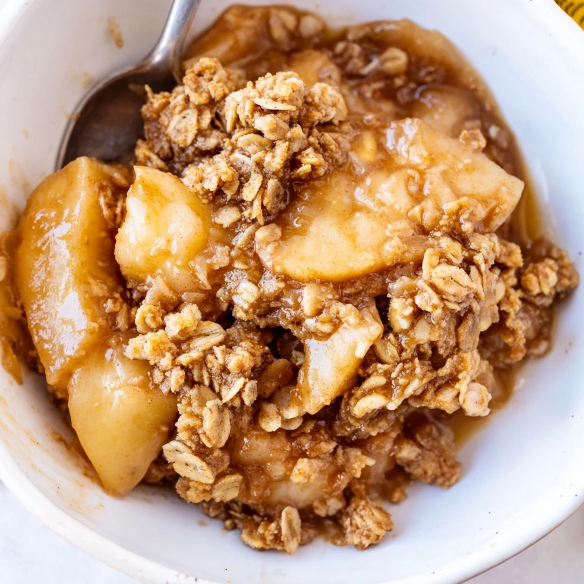 Creamy vanilla ice cream melting over a scoop of homemade crockpot apple crisp dessert