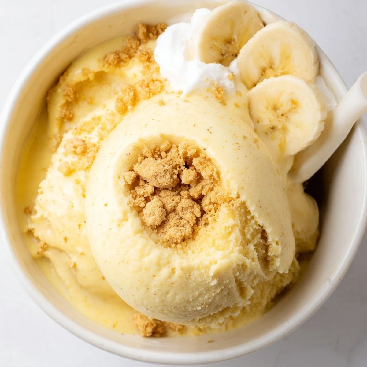 Scoops of chilled Ninja Creami Banana Cream Pie Ice Cream, banana slices garnish