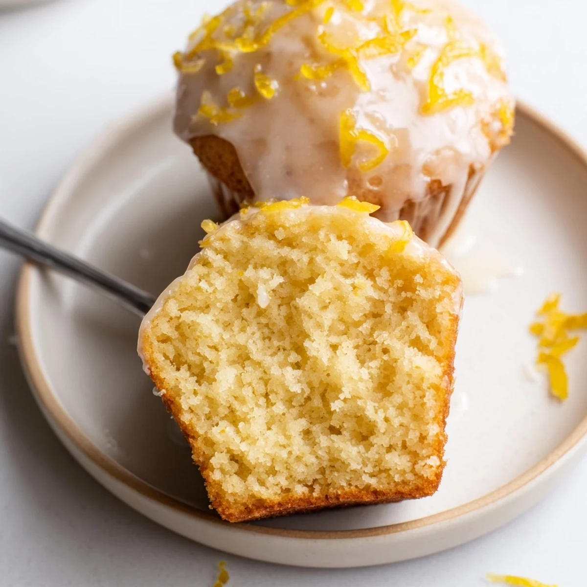 Glazed Lemon Ginger Muffins dusted with zest, steaming beside a teacup.