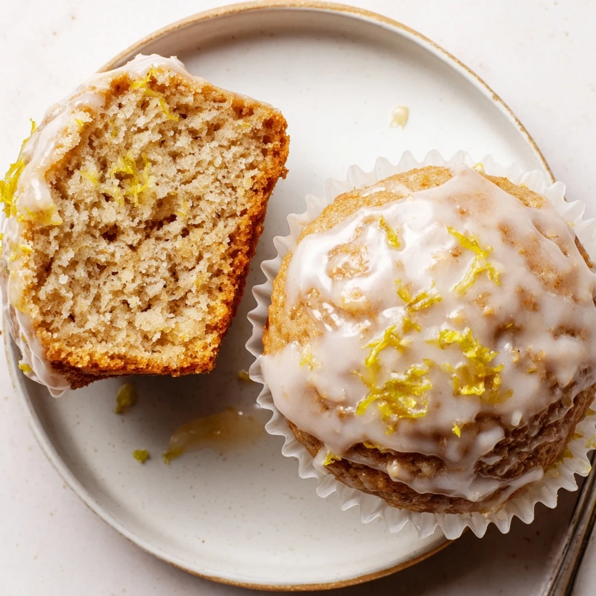 Fresh Glazed Lemon Ginger Muffins lined in paper cups, sticky citrus glaze.