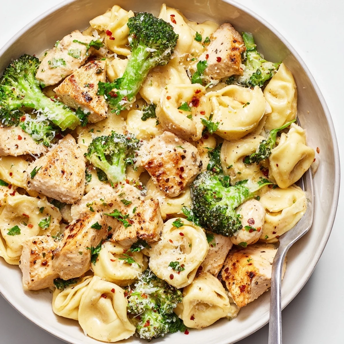 Skillet of Creamy Garlic Parmesan Tortellini Chicken Broccoli Recipe with golden seared chicken bites