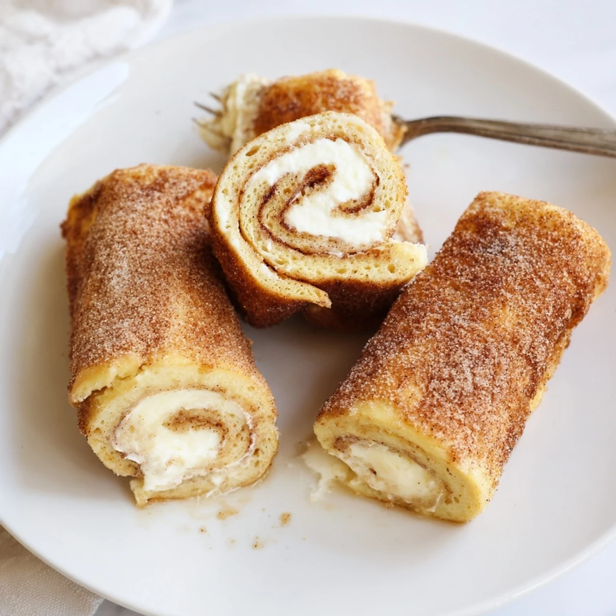 Cinnamon Roll French Toast Roll Ups sliced, gooey cream cheese oozing, served warm