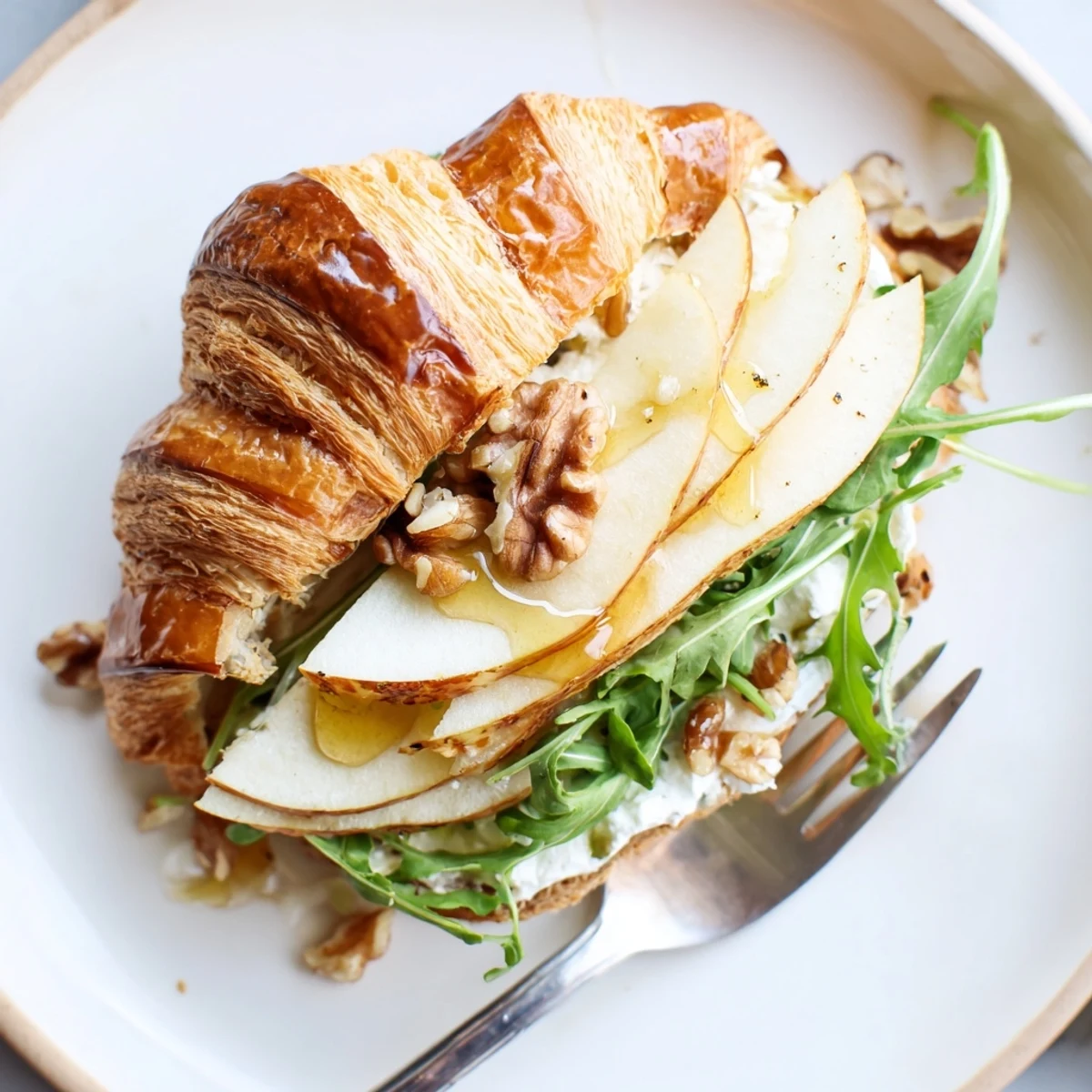 Sliced Apple Goat Cheese Croissant Sandwich on cutting board, drizzled honey glistening