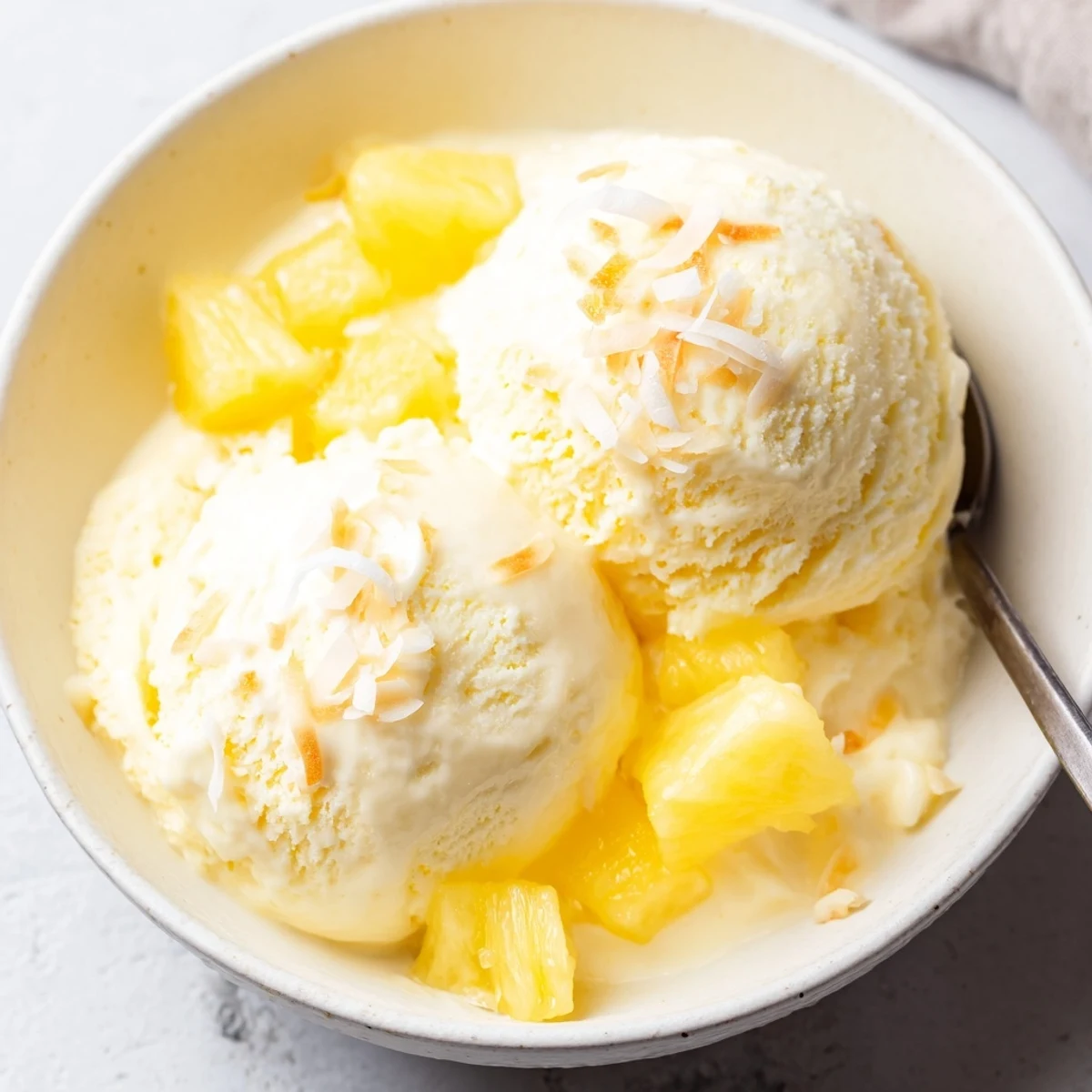 Homemade churned Creamy Pineapple Ice Cream Recipe melting slightly, ready to serve