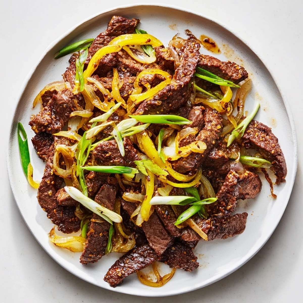 Chinese-style crispy beef and onion stir fry served steaming hot with tender meat and golden vegetables