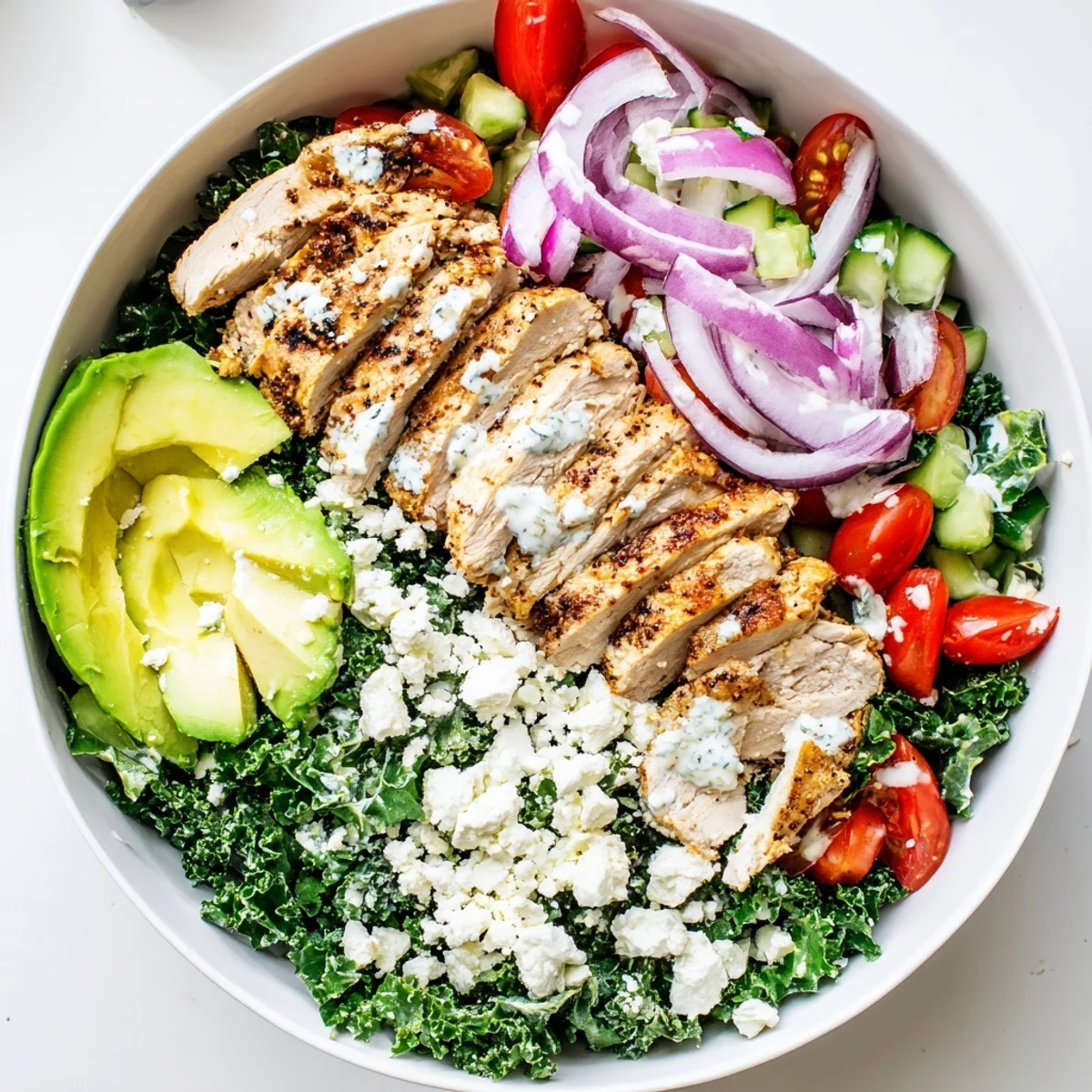 Colorful marinated kale and chicken bowl topped with fresh avocado and vegetables