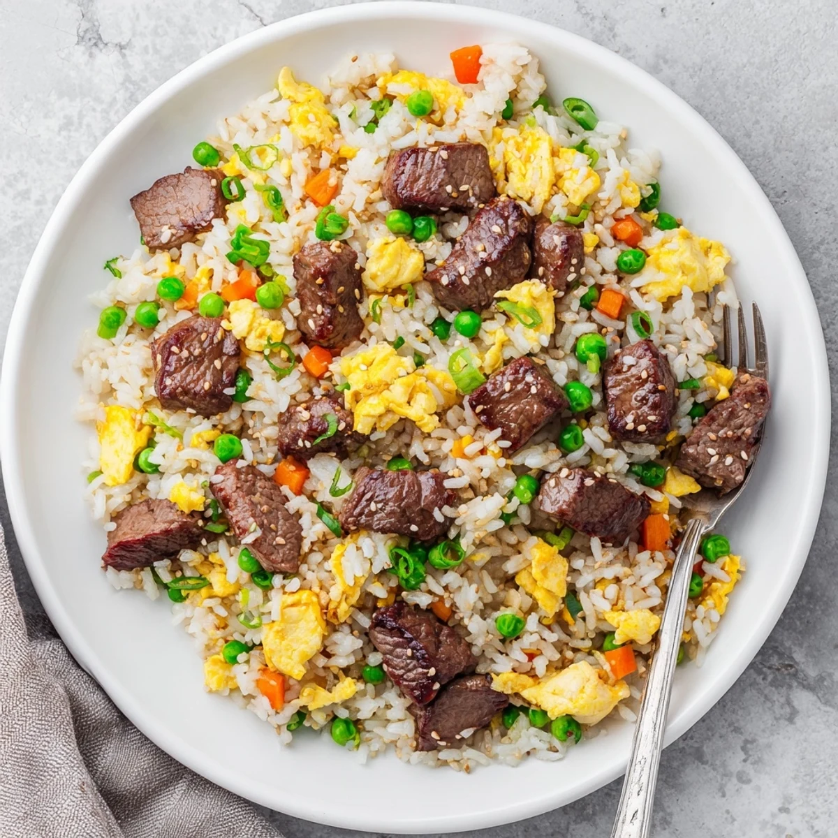 Blackstone hibachi steak fried rice featuring tender beef cubes with colorful vegetables in a sizzling griddle-cooked dish