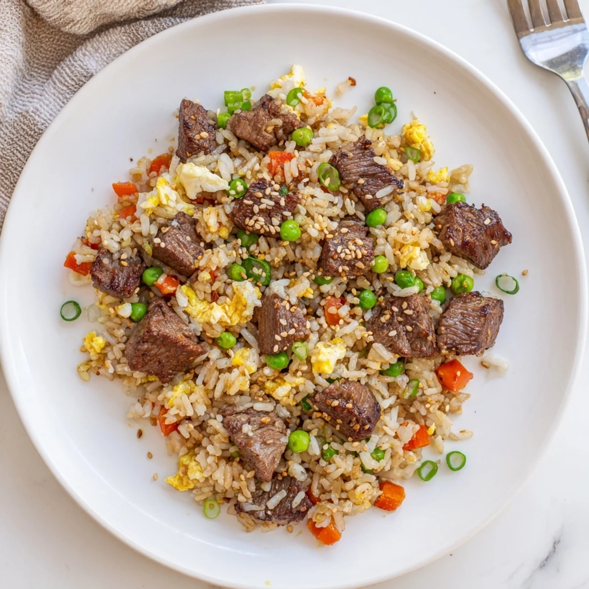 Steak fried rice topped with sesame seeds and fresh green onions, a hearty main dish packed with hibachi flavors