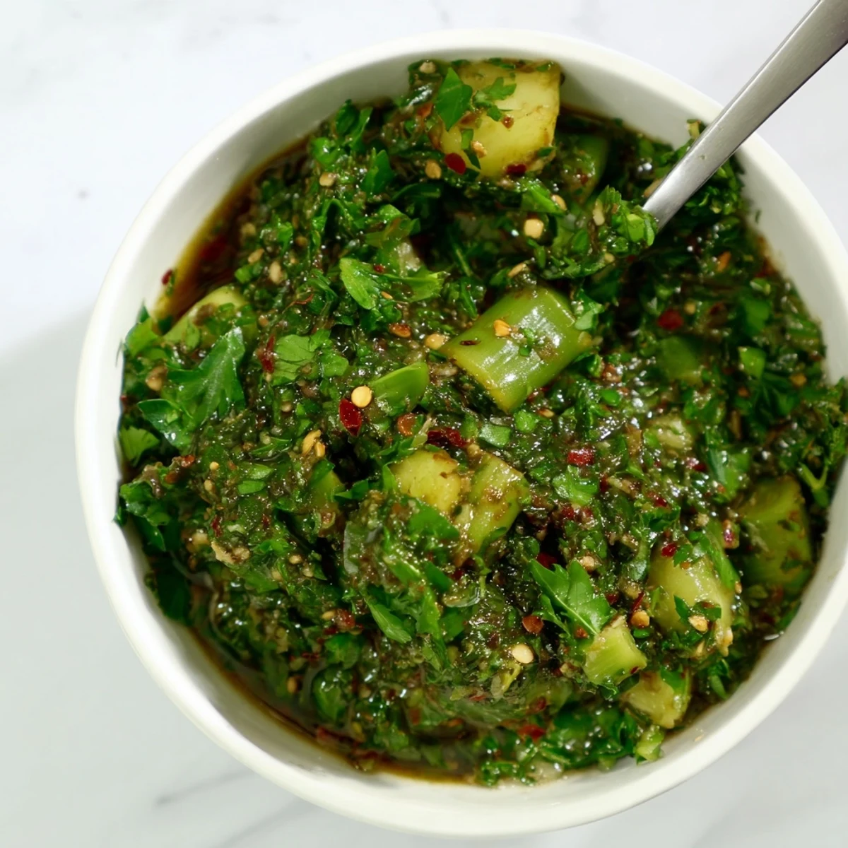 Vibrant green garlic scape chimichurri sauce drizzled over grilled steak and vegetables