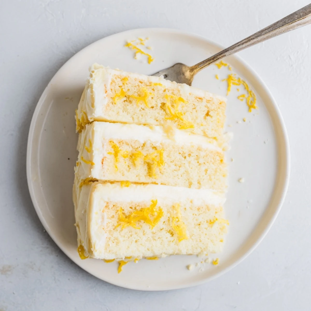 Three-tiered lemon layer cake with tangy curd filling and fluffy white buttercream frosting