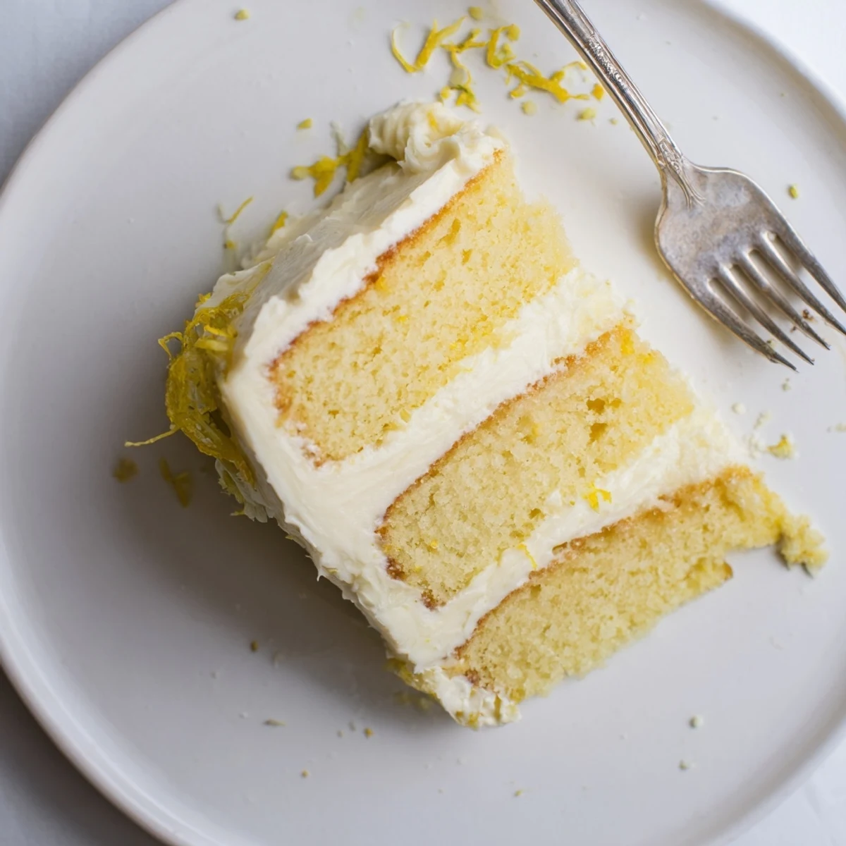 Slice of zesty lemon layer cake showcasing tender yellow sponge and silky lemon buttercream