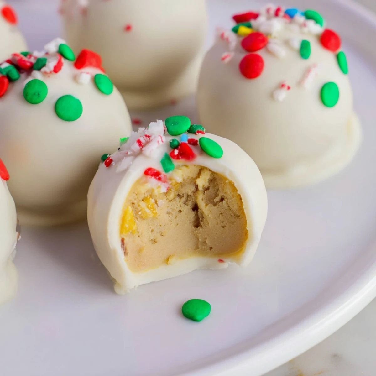 Snowy white chocolate covered Golden Oreo balls arranged on a decorative platter with colorful edible glitter and sprinkles