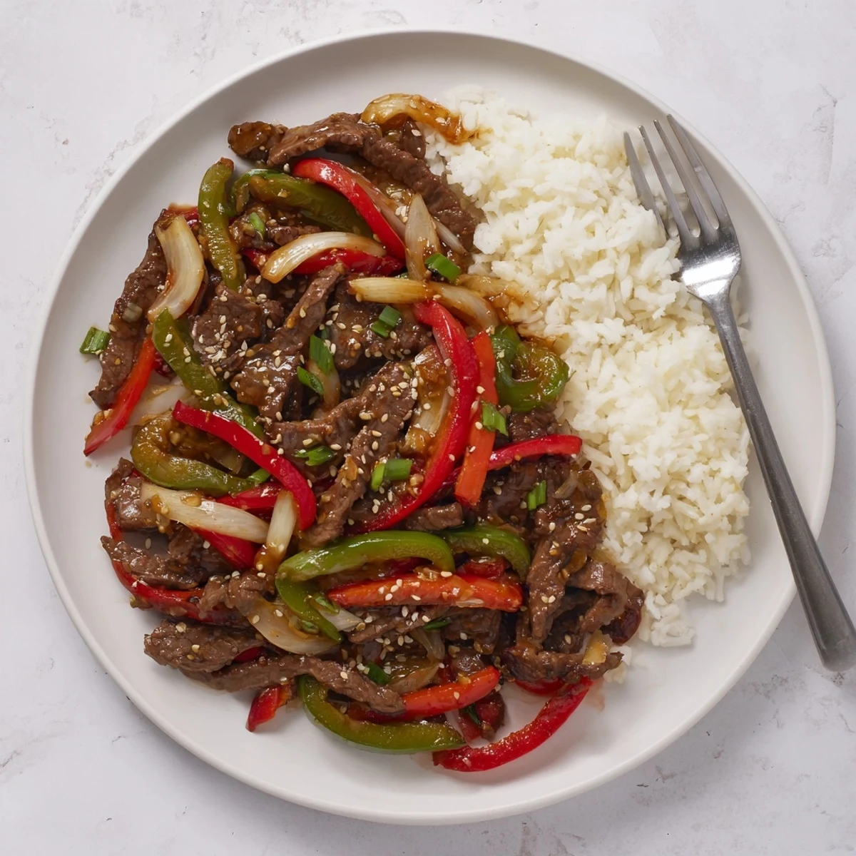 Close up of spicy beef stir fry with chili garlic featuring vibrant red and green peppers in a rich glaze