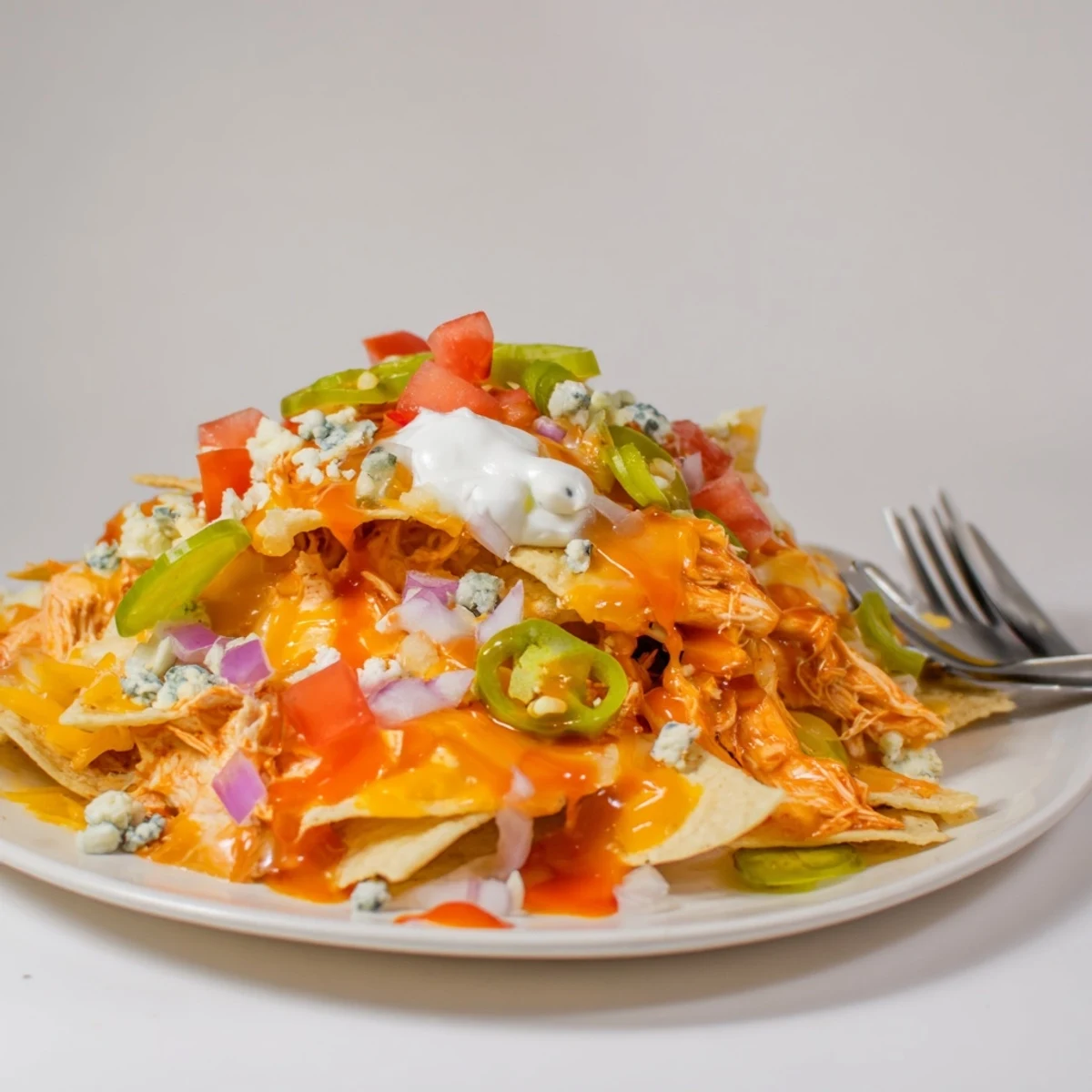 Crispy tortilla bed topped with steamy Buffalo Chicken Nachos, melted cheese bubbling