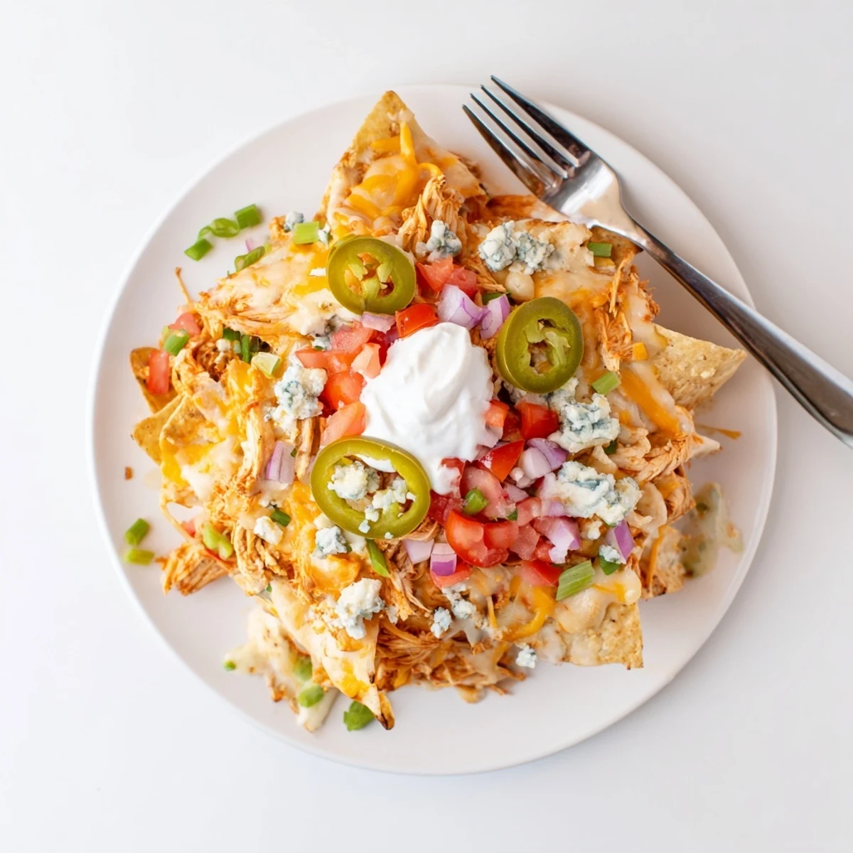 Spicy Buffalo Chicken Nachos layered with jalapeños and sour cream, ready to share
