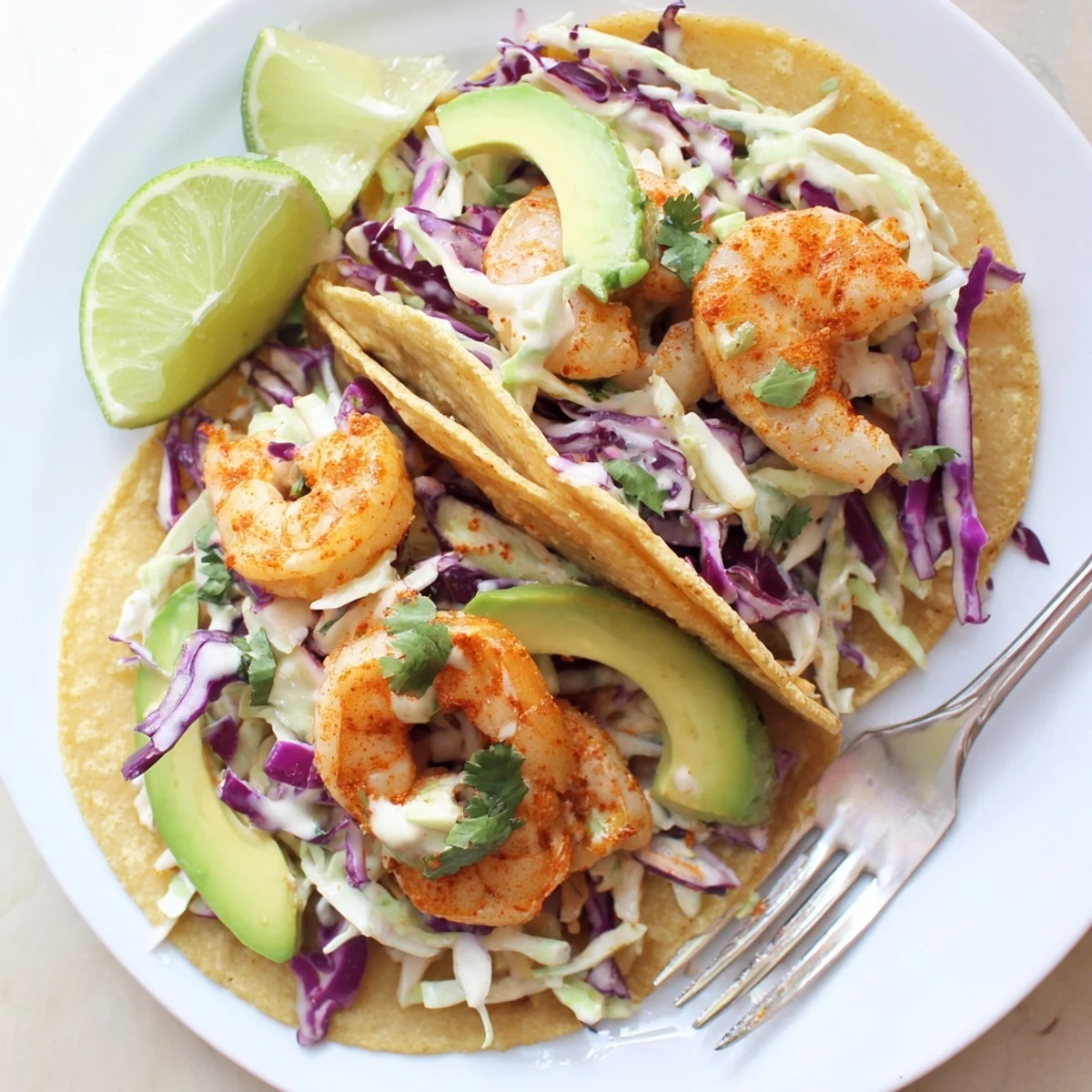 Spicy shrimp tacos piled high with creamy garlic cilantro lime slaw on warm tortillas