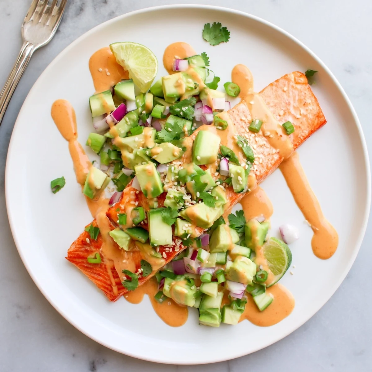 Golden baked Bang Bang Salmon topped with vibrant avocado cucumber salsa and sesame seeds