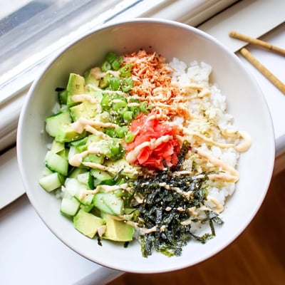 Vibrant California roll sushi bowl featuring imitation crab, avocado, and cucumber strips drizzled with spicy mayo