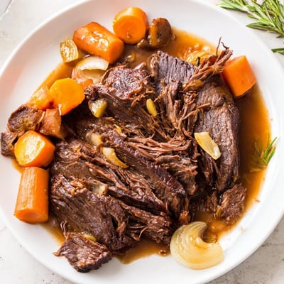 Golden seared perfect pot roast surrounded by aromatic vegetables and fresh herbs